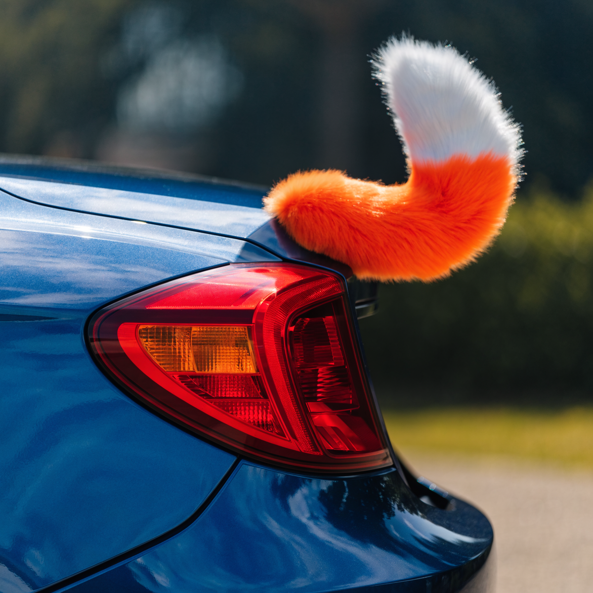 Orange and white wagging tail on the rear corner of a metallic blue sports coupe