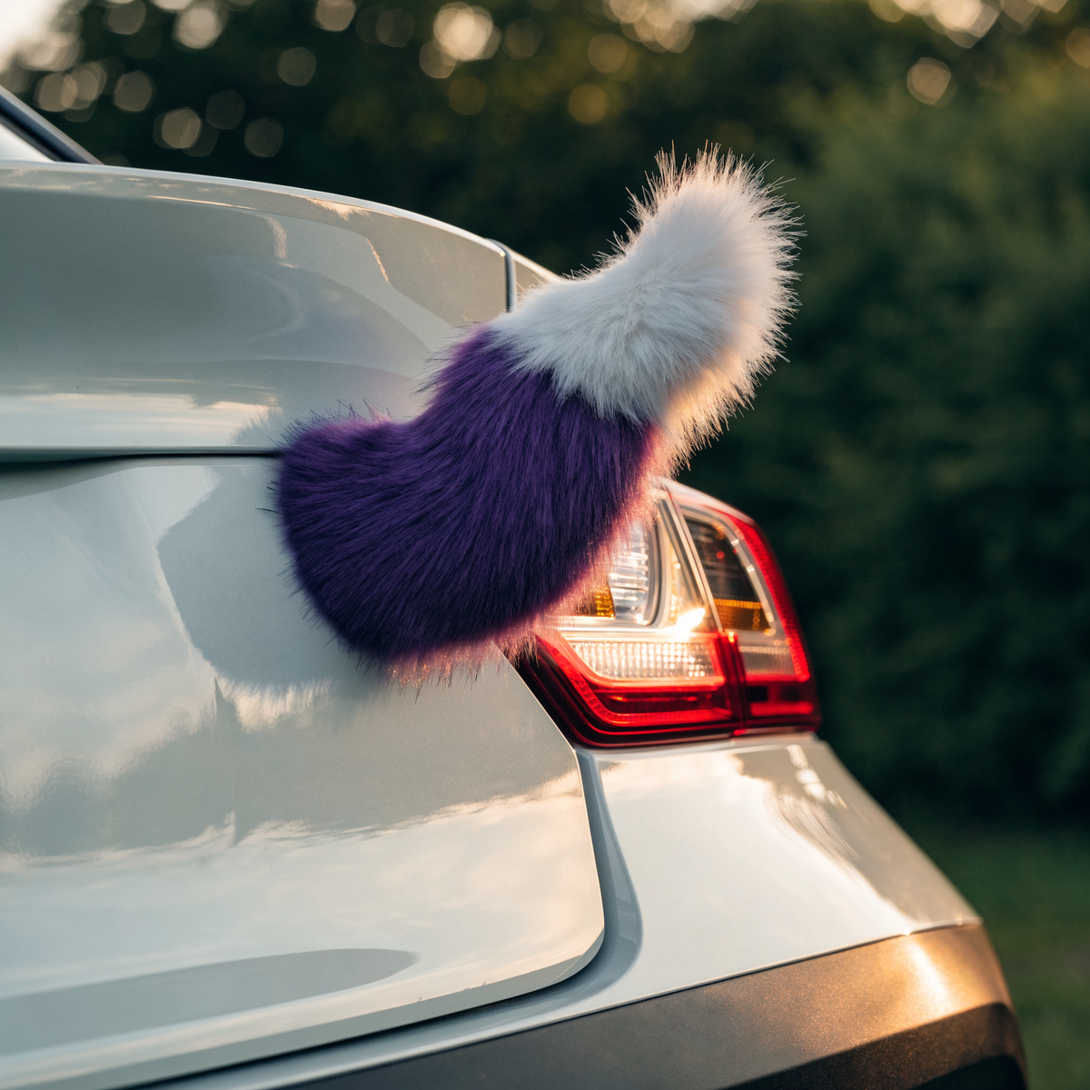 Purple and white wagging tail mounted on the boot lid of a white hatchback car